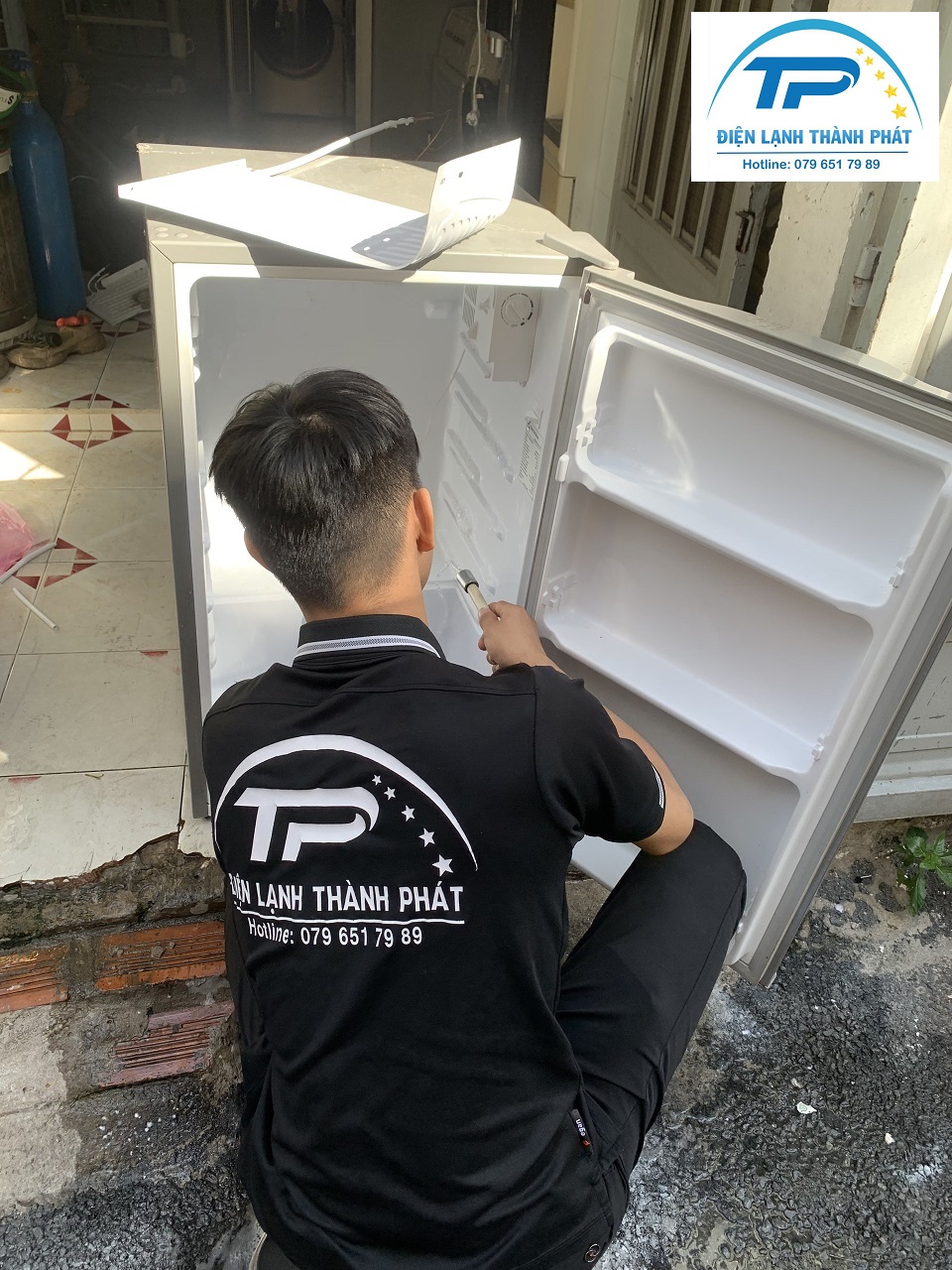 Nhân viên thực hiện thao tác chuyên nghiệp khi sửa tủ lạnh cho khách hàng.